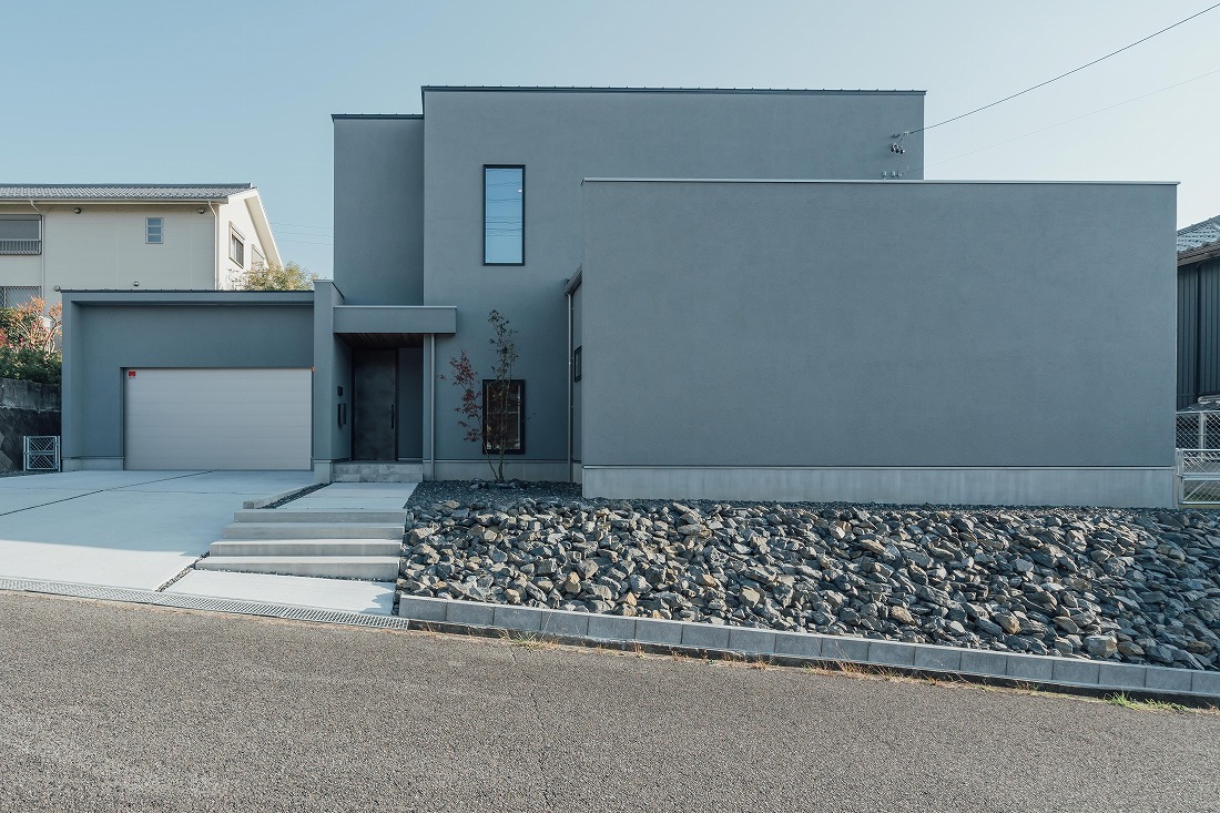 チェックハウス｜モダンなデザインが魅力の住宅外観。シンプルな形状と堅牢な壁面が、スタイリッシュでありながら迫力を感じさせる。