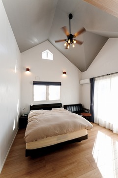 高い天井とシャンデリアが印象的な寝室。大きな窓から自然光が降り注ぎ、心地よい朝を迎えられる空間。リラックスできる家具の配置が魅力。