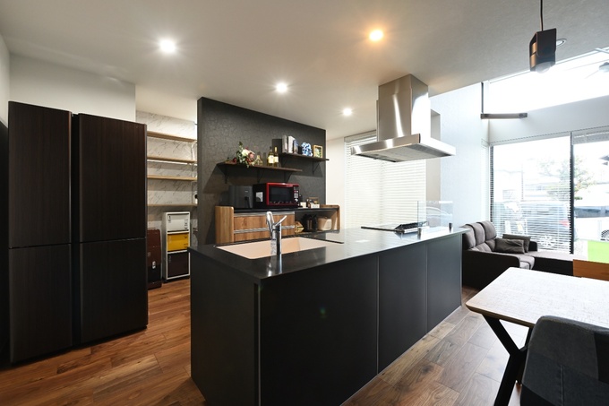 木目調のフロアとブラックのアイランドキッチンが魅力的なデザイン。開放的なワークスペースで実用性と美しさを兼ね備えている。