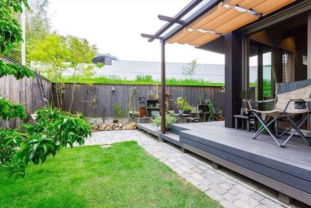 温戸ライフ【自然素材、間取り、インテリア】表通りからは想像もつかない、開放感あふれるプライベートガーデン。軒のあるウッドデッキでくつろぐひとときはまさにリゾート気分。ウッドフェンスで外からの視線を遮りながら、BBQやグランピングを楽しめる。このほか、テーマの違う3つの庭がある