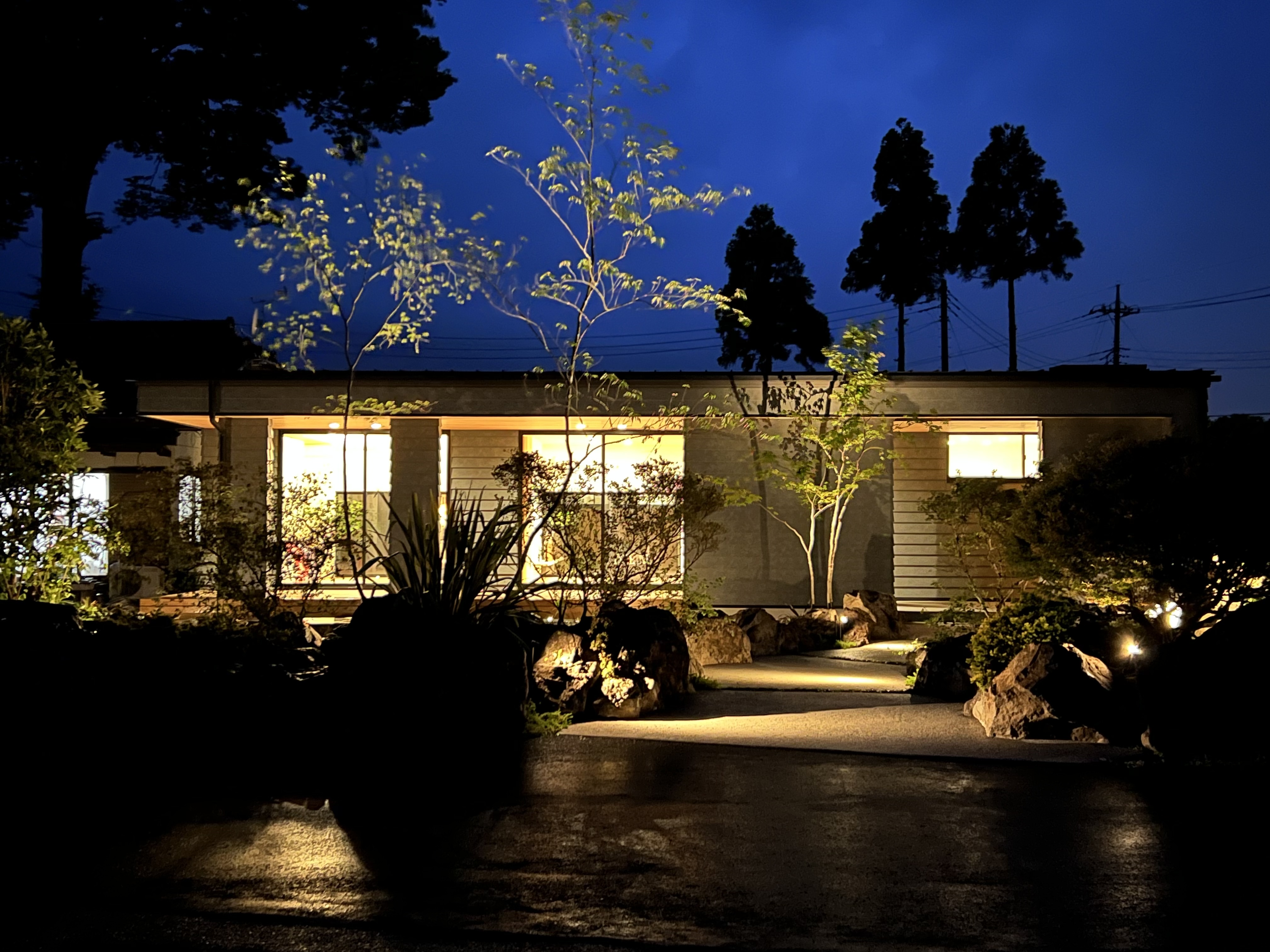 伸興建設｜夜の庭園が美しくライトアップされた住宅の外観。落ち着いた風景に包まれた家は、静寂と自然を感じる場所である。