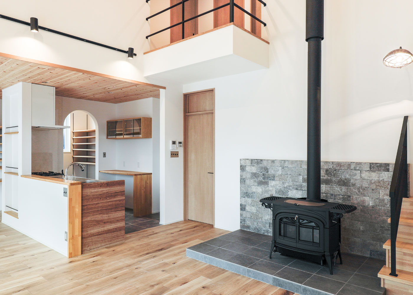 彩羽工藝舎【デザイン住宅、間取り、平屋】2階への吹き抜けが開放感のあるLDK。家の中心に据えられた薪ストーブが家全体を暖める。各部屋へのドアには欄間窓をつけ、温めた空気が家全体を回るように工夫した