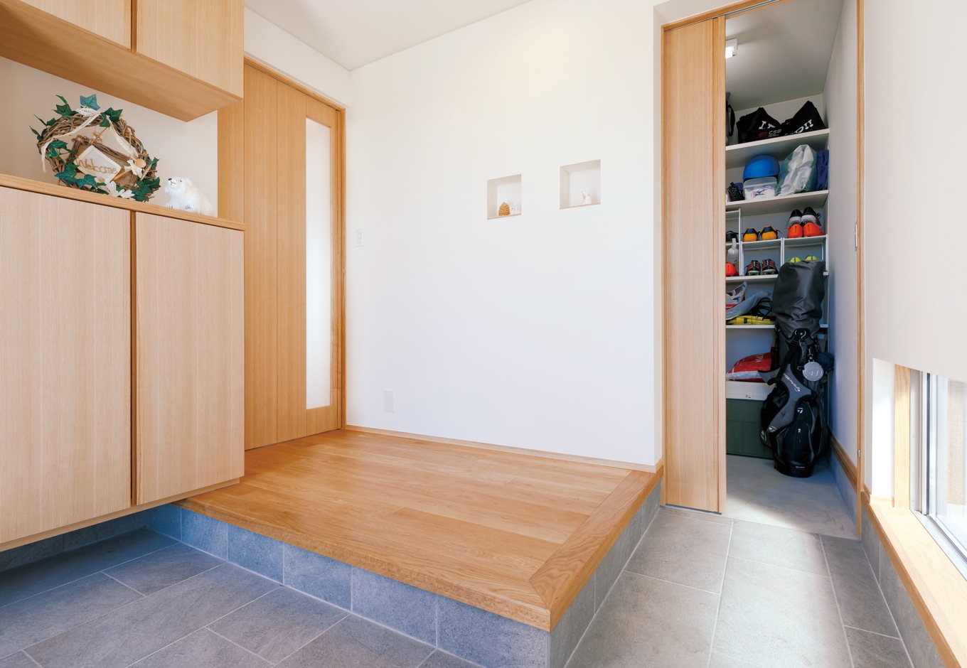 神谷綜合建設 カミヤの家【自然素材、間取り、インテリア】土間をL字型に設けた玄関。間接照明やニッチでオシャレに演出。足元の明かり窓で、視覚的な空間の広がりも感じる