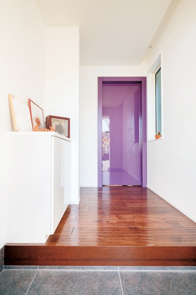 玄関を上がると足裏に優しく伝わるのは、スクラッチ加工をした『納得』オリジナルの床材の凹凸。アクセントカラーのイタリア直輸入の高級リビングドアもインパクト大