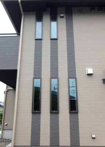 玄関横の外壁には、アクセントとしてバルコニーと同じ色合いのダークブラウンで3本のラインを描き、縦すべり窓を配置