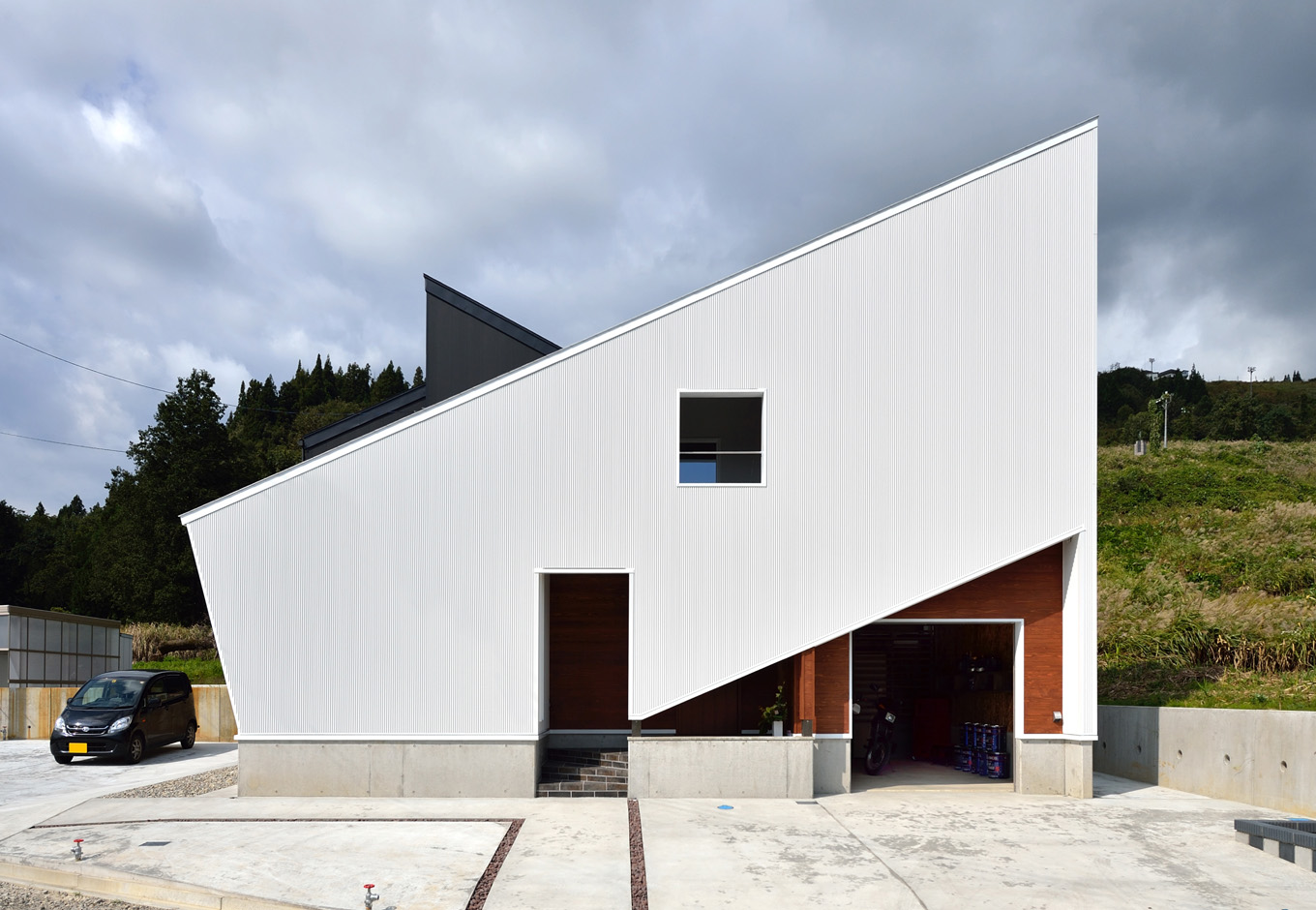 SEIEN ARCHITECT【デザイン住宅、建築家、インテリア】急勾配の屋根が特徴的な外観。プライバシーに配慮して室内につながる玄関ドアは壁で隠してある。右側はビルトインガレージの入り口