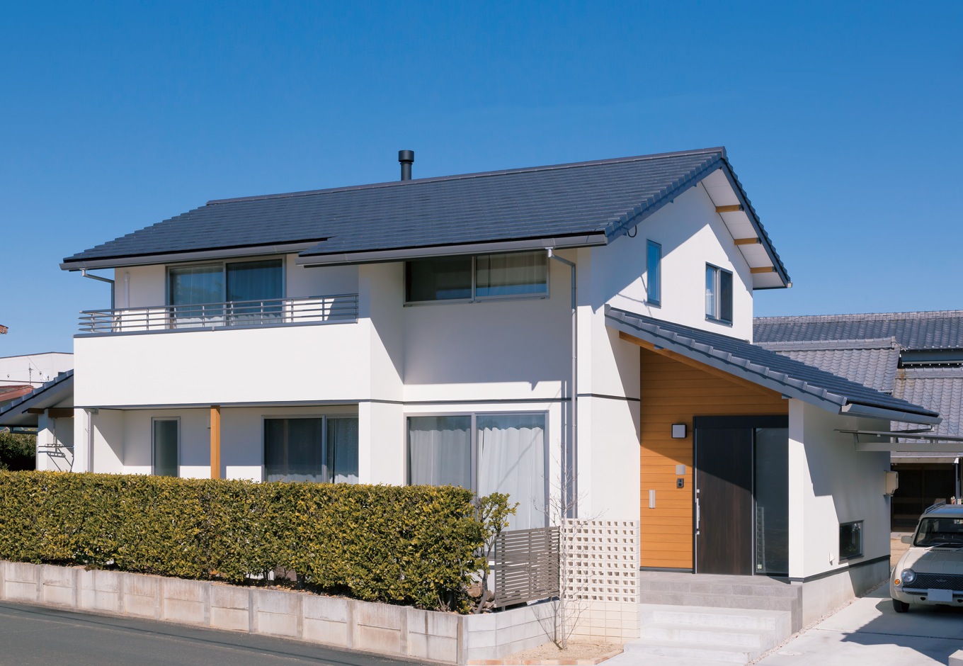 神谷綜合建設 カミヤの家【自然素材、間取り、インテリア】切妻屋根に白い塗り壁がマッチした外観。アプローチや玄関まわりは空洞ブロックの門塀や板張りの外壁でアクセ ントを付け、シンプルな中にも素材や色のバランスの良さがうかがえる