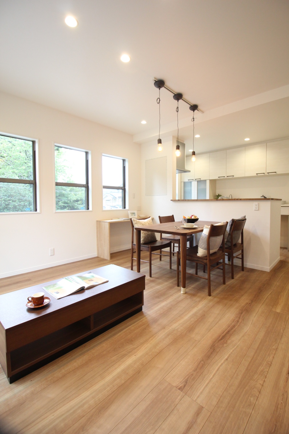 小野田産業～designers house project～｜シンプルで洗練された子世帯のリビングダイニング。木目調のフローリングが温かみを演出し、ナチュラルな雰囲気を引き立てる。テーブル照明がアクセントになっている。