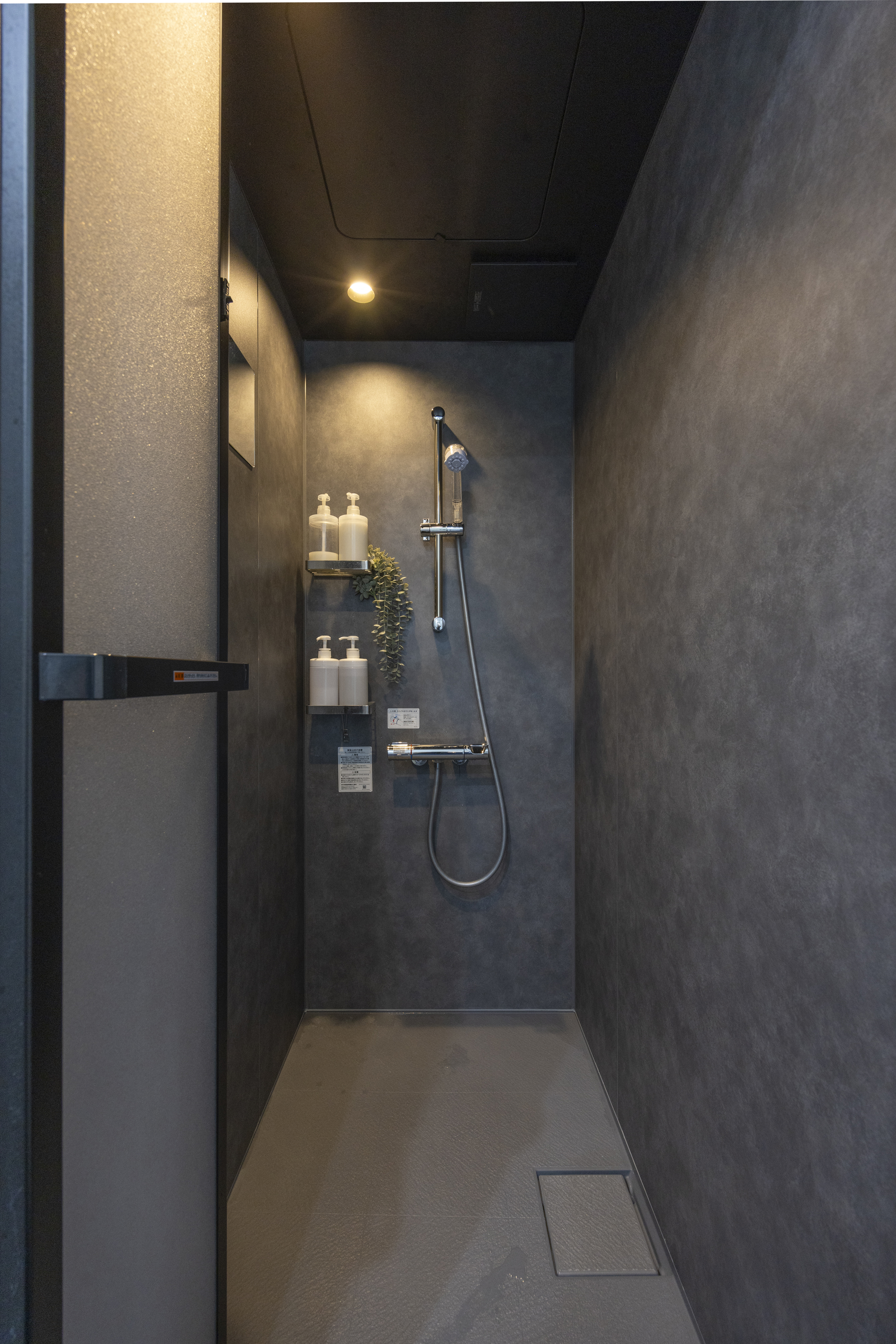 広島建設 セナリオハウス｜モダンなシックなデザインのシャワールーム。落ち着いた色調の壁に、シンプルなシャワー設備がスタイリッシュさを際立たせています。透明感のあるドアが空間を開放的に演出。