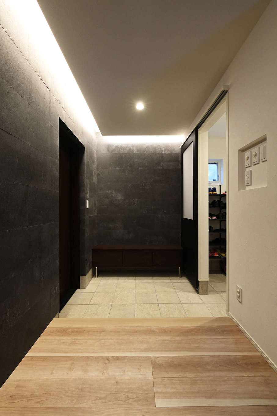 トーリンホーム【デザイン住宅、子育て、間取り】玄関からリビングに至る壁にも「ソリド」を採用し、内と外の一体感を強調。間接照明を用い、ホテルライクで洗練された雰囲気を演出。シューズクロークから手洗い場を抜けてキッチンに至る動線も確保されている