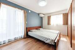 バルコニーと直結した8畳の主寝室。ネイビーのアクセントクロスで柔らかな雰囲気を演出。東側の小窓を開けると吹抜けとつながる