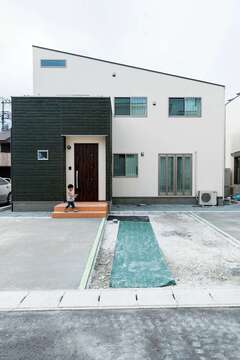 コテむらを残して仕上げた外壁は約60年間メンテナンスフリー。玄関まわりのみ深緑のサイディングでアクセントをつけた