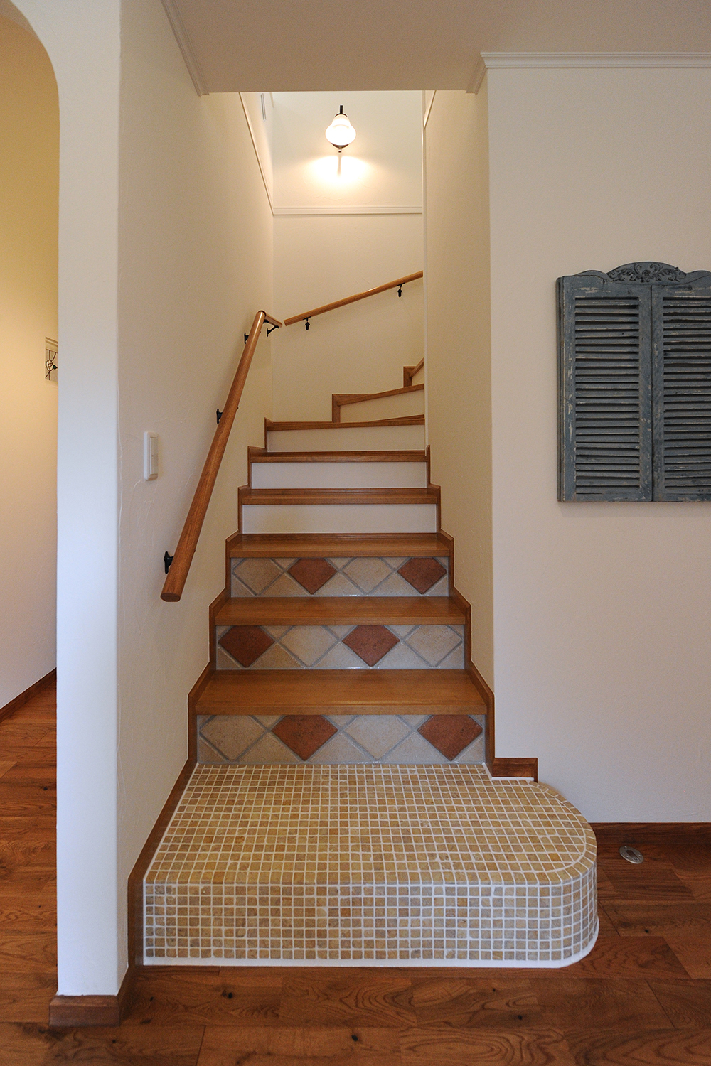 アイディートゥー 一級建築士事務所【デザイン住宅、輸入住宅、間取り】独特なデザインに目を奪われる階段。踏み板に無垢材、蹴込み板にタイルを張ってニュアンスを出した。年齢を重ねても利用しやすいよう、傾斜と段数も計算し尽くされている