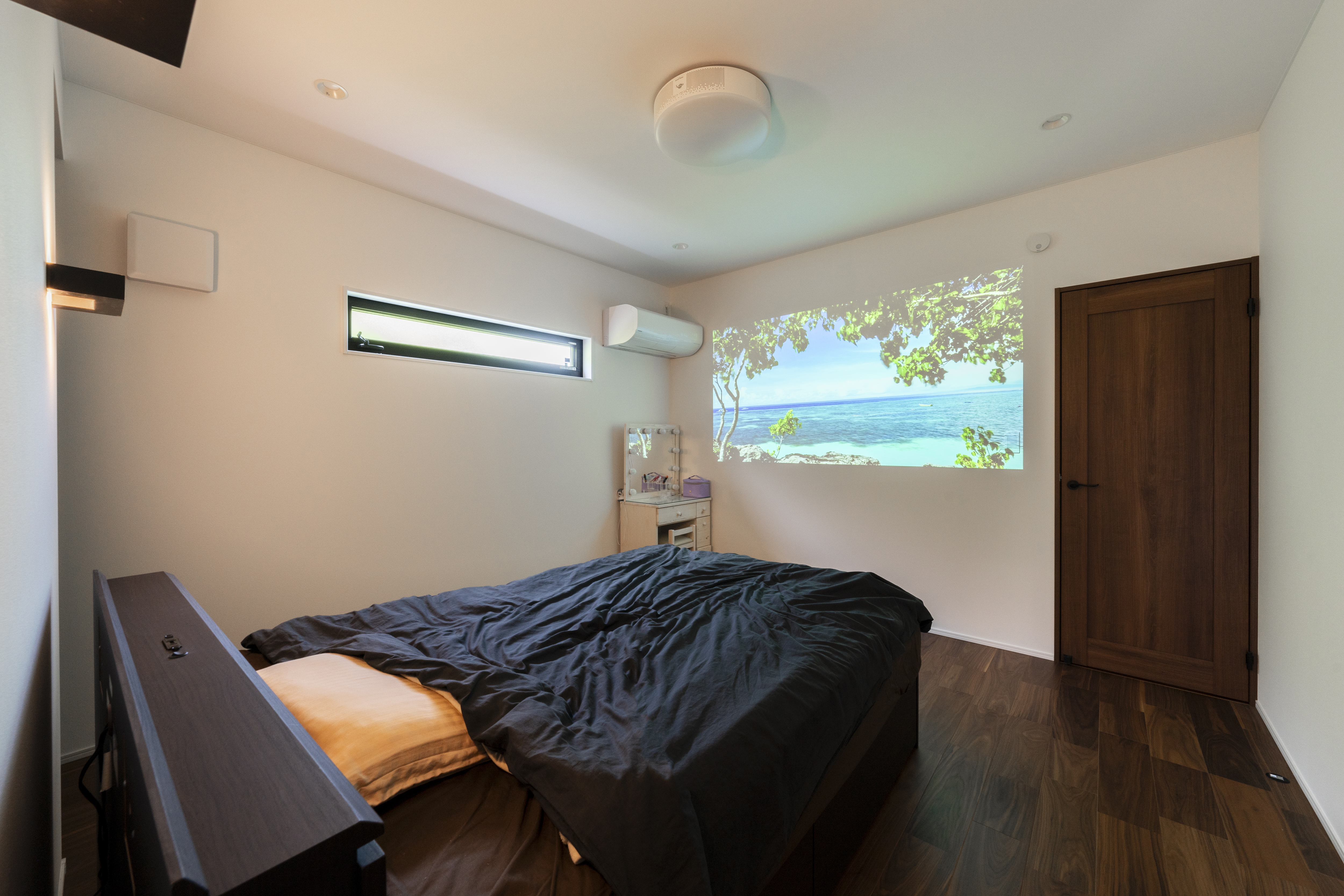 広島建設 セナリオハウス｜プロジェクターで壁に映像を映し出せる寝室。落ち着いた色調のインテリアが心地よい空間を演出しています。