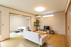 モダンなデザインのリビングルームで、快適なソファと落ち着いた色調のインテリアが調和している。広がりのある空間が心地良い。リビングの向こうにはくつろぎの和室が。