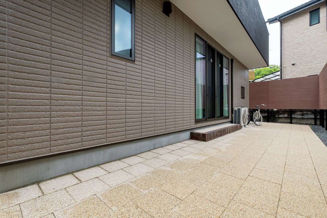 甲静ハウジング【子育て、間取り、屋上バルコニー】3方を囲まれてプライバシーが保たれたタイルデッキの庭。隣家の緑を借景にしたゆとりの空間だ