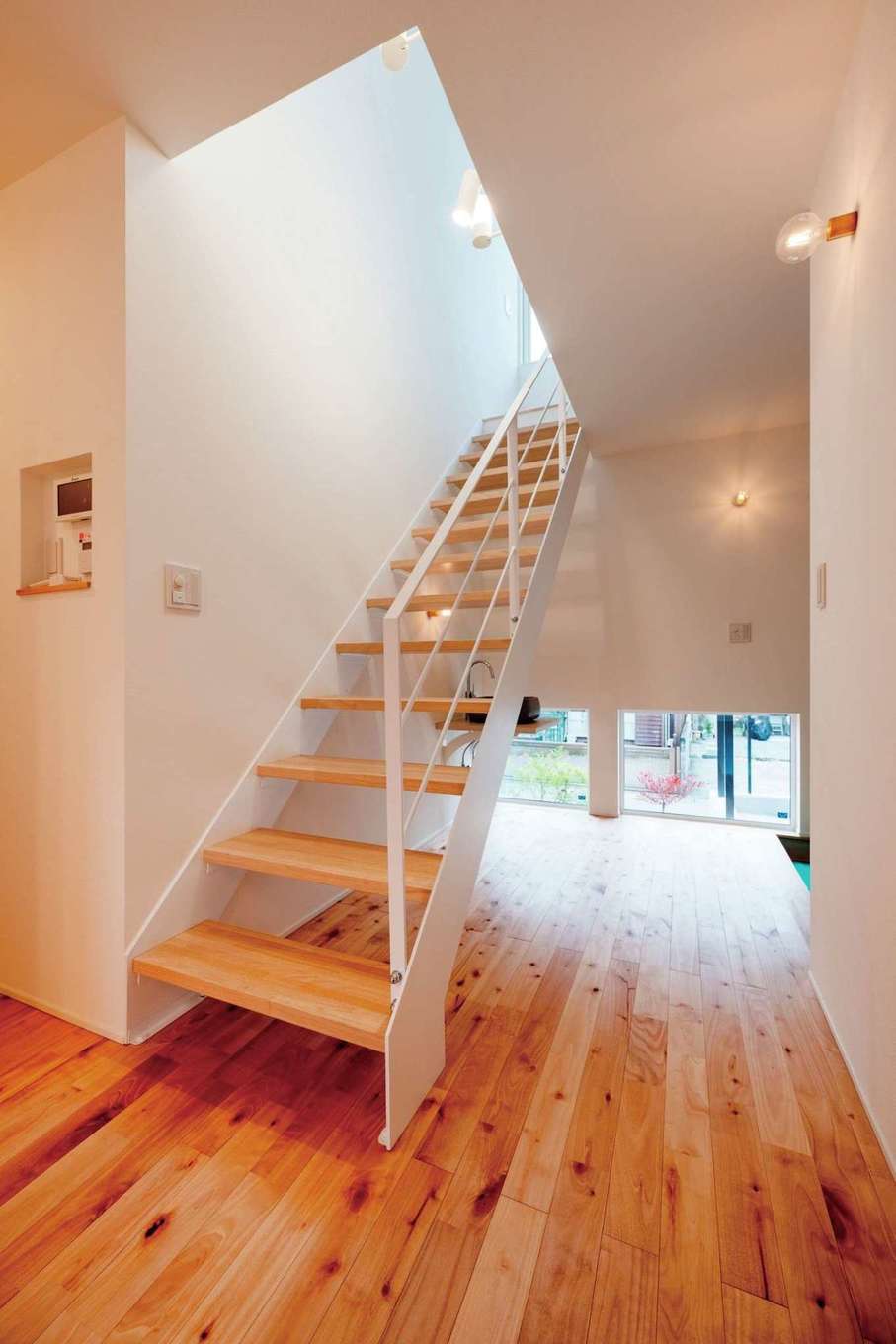 ハウスプラン（R＋house沼津・富士）【デザイン住宅、省エネ、間取り】玄関ホール。白いスチール階段が空間になじみ、地窓が明るさを取り込む。1階の個室に続く動線はコンパクトにまとめている