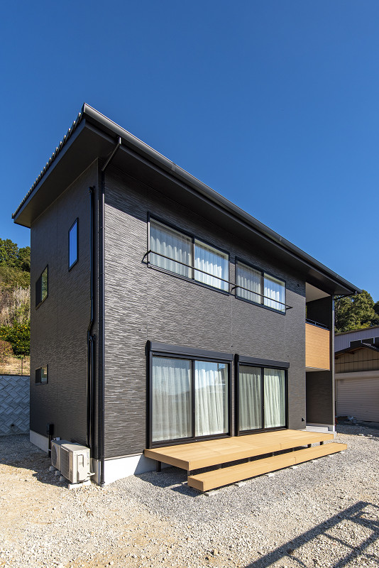 トキワハウス デザイン アンド ビルド（常盤工業）｜黒い外壁が特徴的な２階建て住宅。広い庭と木製デッキがリラックスできる空間を提供している