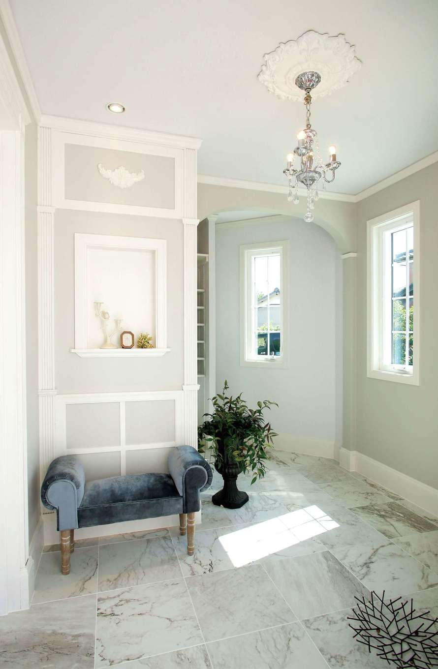 スカイグラウンド【デザイン住宅、輸入住宅、インテリア】玄関ホールは「エレガント」をテーマにデザイン。リビングとダイニングに濃さの違うブルー系の壁を使ったのに対し、ここは淡いパープル系の壁に。アーチの垂れ壁など、直線と曲線がバランス良く交差し、訪れるゲストの五感を心地よく刺激する。輸入住宅の施工実績が豊富で、海外の住宅事情に詳しい同社ならではの提案力が光る