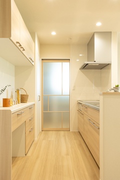 木目調のキャビネットと白い壁が、明るく清潔な印象を与えている。全面ガラスの建具が奥行きを感じさせるデザイン。