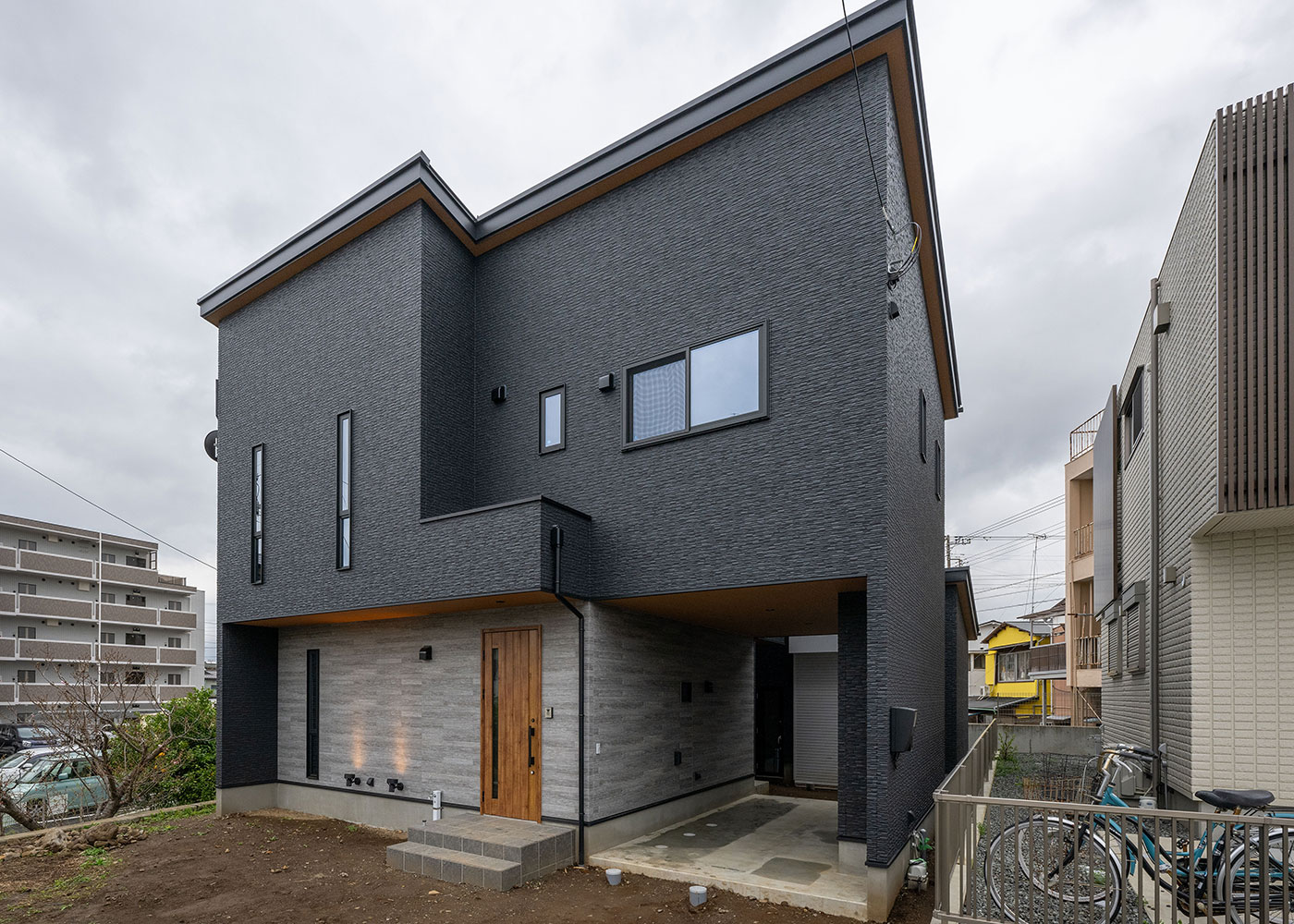irohaco （アヴァンス）【デザイン住宅、間取り、ガレージ】スタイリッシュなフォルムが印象に残るシンプルモダンな外観。グレーのガルバリウム鋼板と石目調のサイディングが絶妙のバランスで調和している。インナーガレージは車とバイクの両方を格納でき、ほとんど雨に濡れることなく玄関にアクセス可能だ