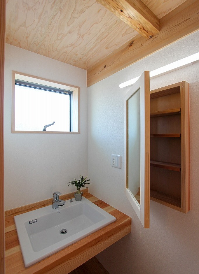 アクトホーム【自然素材、省エネ、間取り】2階ホールに設けた洗面コーナー。右手の鏡を開けると、収納になっていて便利。