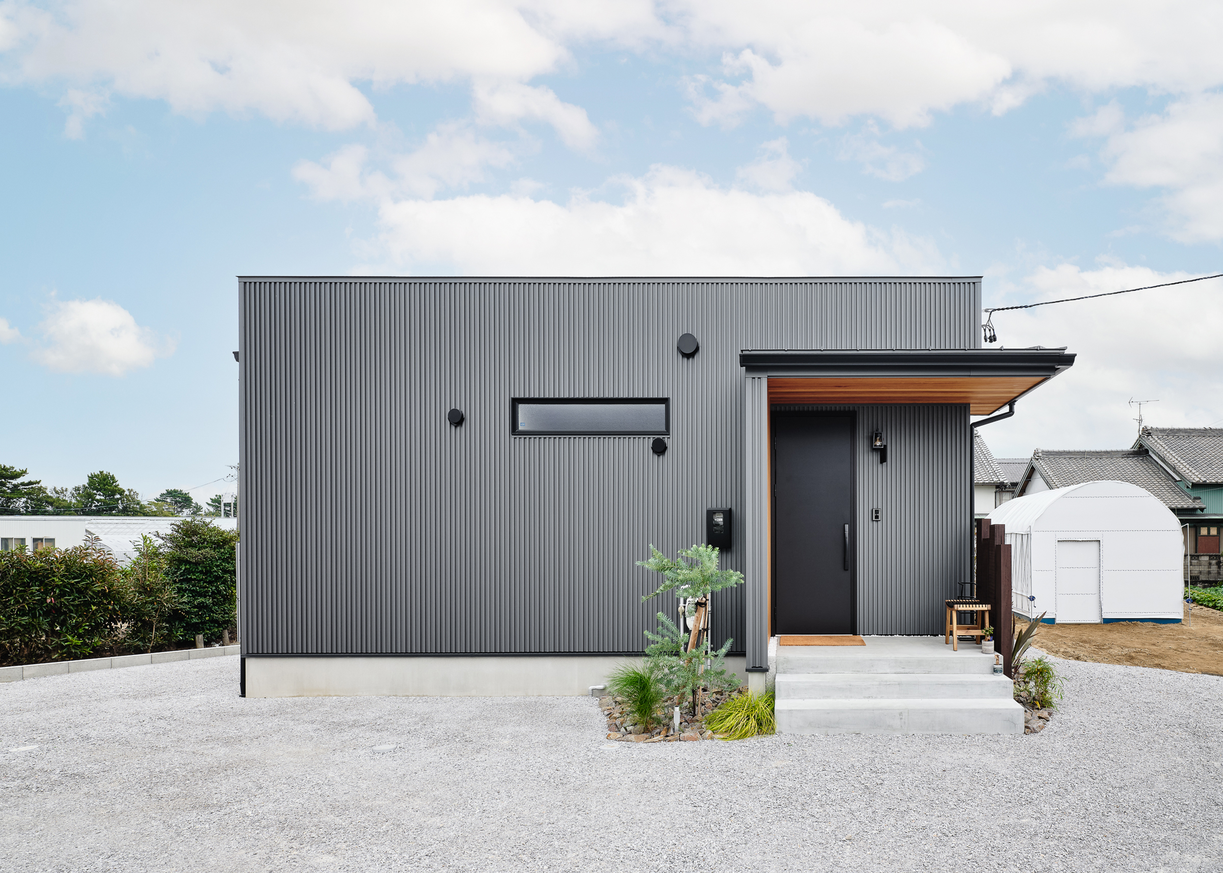 平屋建築ブルーハウス【ペット、建築家、平屋】グレーの箱型のシンプルな外観。道路側には窓を極力設けず、プライバシーを確保。玄関ポーチにはレッドシダーの板張りを採用し、アクセントを付けた