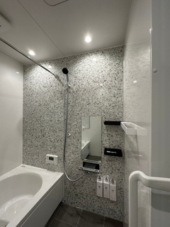 モダンなバスルームが広がる。壁のタイルがスタイリッシュで、清潔感漂う空間である。リラックスできる浴槽も完備。