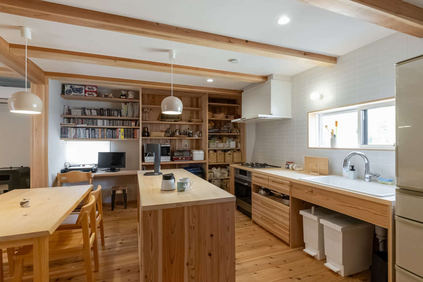 有吉住宅【収納力、自然素材、間取り】LDKをできる限り広く使いたいという思いから、壁付けキッチンに。キズに強いヒノキを使い、収納やダイニングテーブルなども造作
