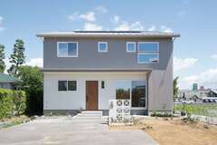 グレーの外壁に花ブロックが映える外観。日照シミュレーションを行い、建物の配置を決めました。