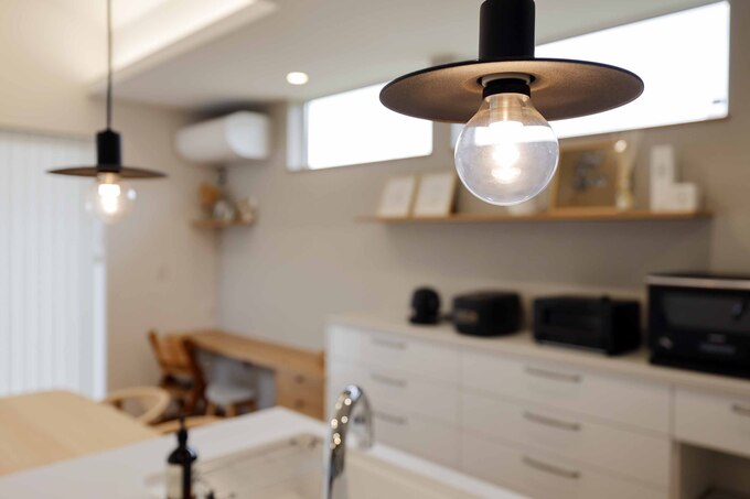 モダンでミニマルなデザインのペンダントライトが特徴のキッチン。機能的なカウンターと収納が整っており、調理が楽しくなる空間である。