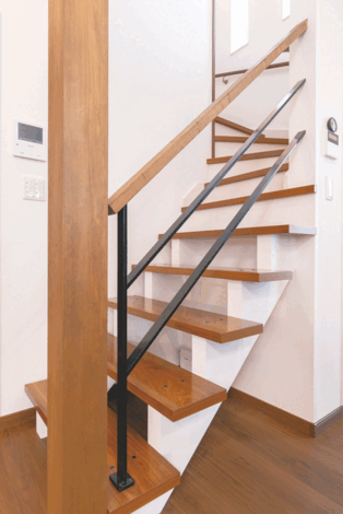 リビングに接する部分はスケルトンにした階段。視覚的にも開放感を感じさせてくれる。手すりはウォルナット色と相性のいいアイアン製に