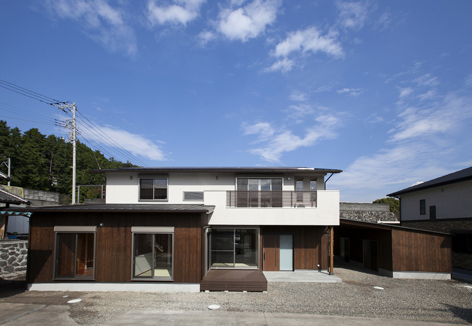 焼き杉の板張りと白い塗り壁のシンプルな外観。駐車場けん作業場と、収納小屋ある