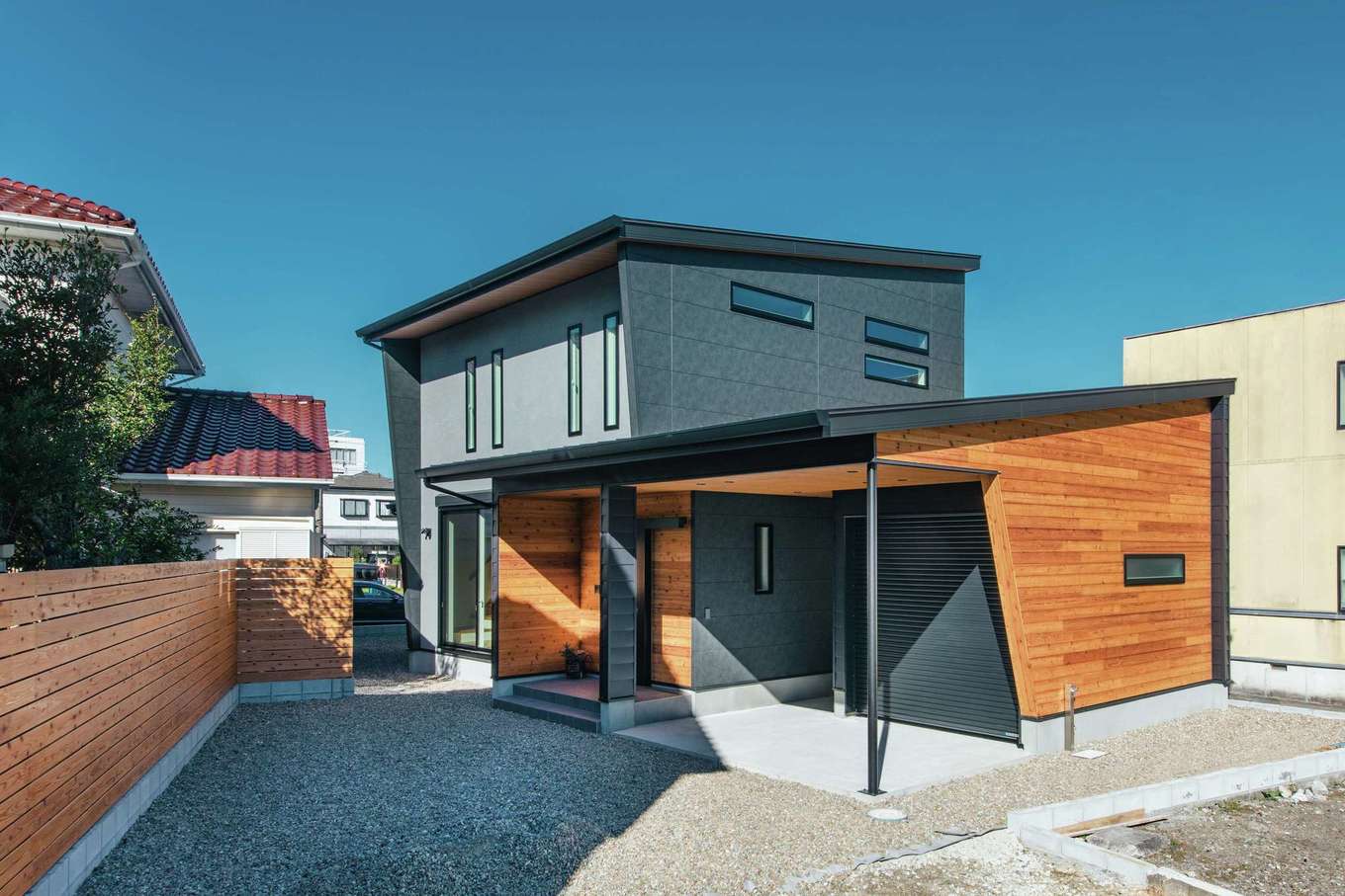 LIXIL住宅研究所 フィアスホーム【デザイン住宅、省エネ、間取り】異素材MIXの外壁が青空に映えるシンプルモダンな外観。インナーガレージ内ではBBQやサーフボードのお手入れができる。長いウッドフェンスはスギ板で造作