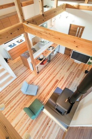 天竜杉の深い香りに包まれたLDK。薪ストーブの輻射熱で家中がほんわかと温まる。キッチンに立つ奥さまの目線がタテ・ヨコに抜け、平屋とは思えない開放感がある