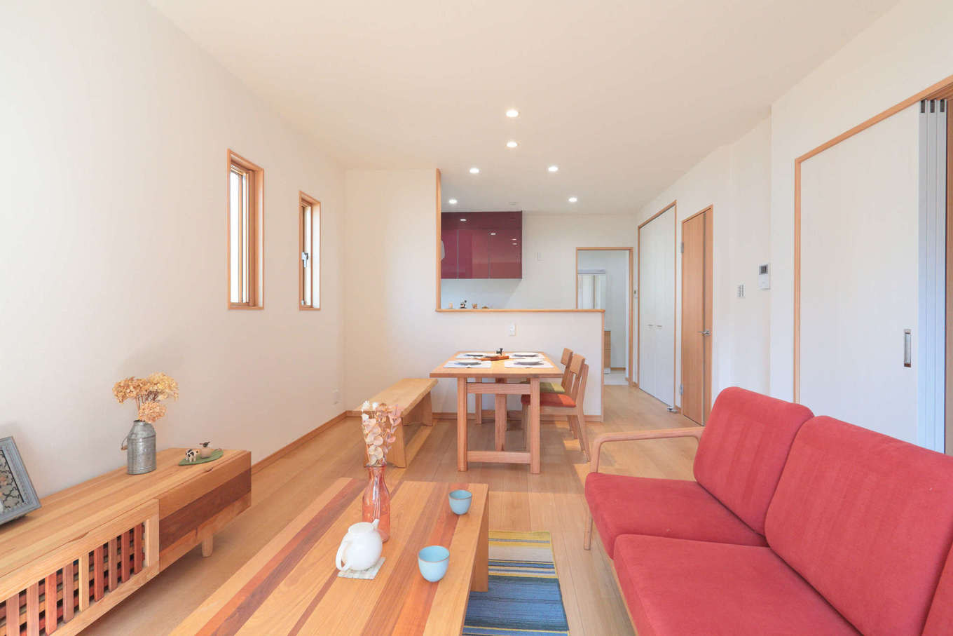 吉川住建【和風、二世帯住宅、自然素材】親世帯のLDKは16畳。赤いソファが挿し色に。テレビボードは造作