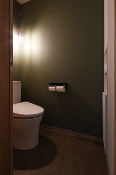 落ち着いた色調のトイレ空間。壁面のダークグリーンが、大人の雰囲気を醸し出し、リラックスできる洗練されたデザインとなっている。
