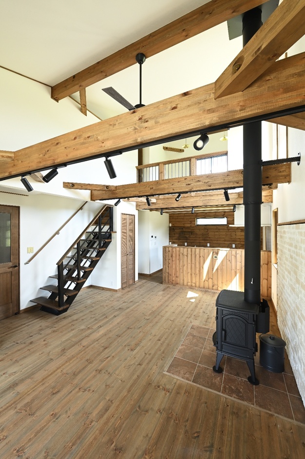 広大なLDK空間。木の梁とストーブが調和し、自然素材を活かした温もりのある居住空間を提供している。