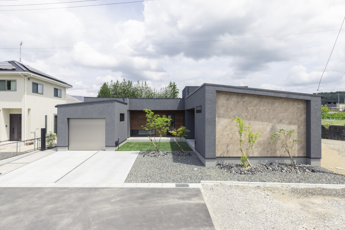 チェックハウス｜モダンなデザインの平屋住宅の外観。グレーの壁と木目の組み合わせが洗練された印象を与える。シンプルながらも個性が光るファサード。