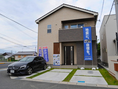 シンプルモダンなデザインの外観。駐車スペースには車が4台停められ、天然芝がアクセントとなっている。
