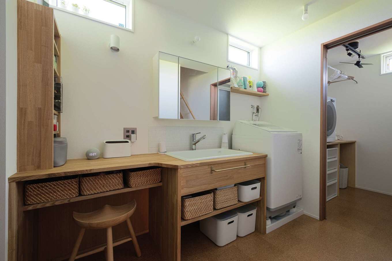 仲田工務店【趣味、自然素材、間取り】収納するモノに合わせて棚のサイズを細かく設計した造作洗面。手前は奥さまのメイクスペースに。奥の脱衣室には「乾太くん」に合わせた作業カウンターと収納も