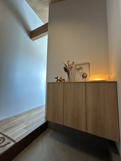 シンプルで洗練された玄関スペース。木製の収納キャビネットには、温もりを感じさせるディスプレイが配置されている。