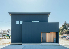 大小の箱が2つ重なったように見える独創的なブラックの外観デザイン。玄関ポーチのレッドシダーがアクセントになっている。さまざまな角度から見えるので、窓を少なくしてプライバシーを確保しつつ、十分な光を取り入れられるように配慮した