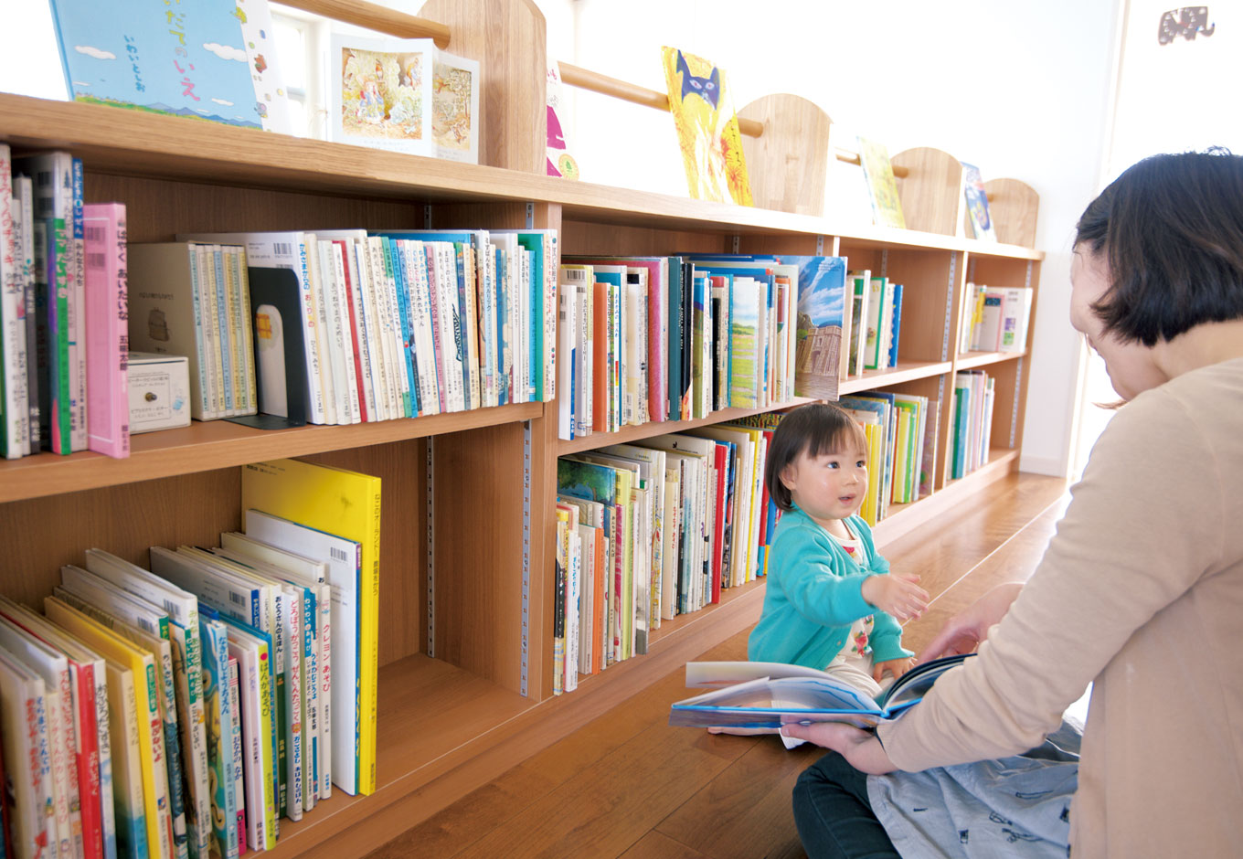 アキヤマ【デザイン住宅、子育て、省エネ】2階のホールに設けられた本棚には、絵本をたっぷり収納。明るく立ち寄りやすい雰囲気なので、子どもの好奇心をくすぐる。親子で素敵な読み聞かせの時間を過ごせる
