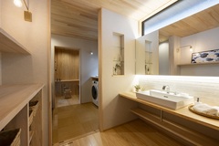 広々とした洗面スペース。大きなシンクと鏡があり、収納棚には余裕があり、使いやすさを重視したデザイン。