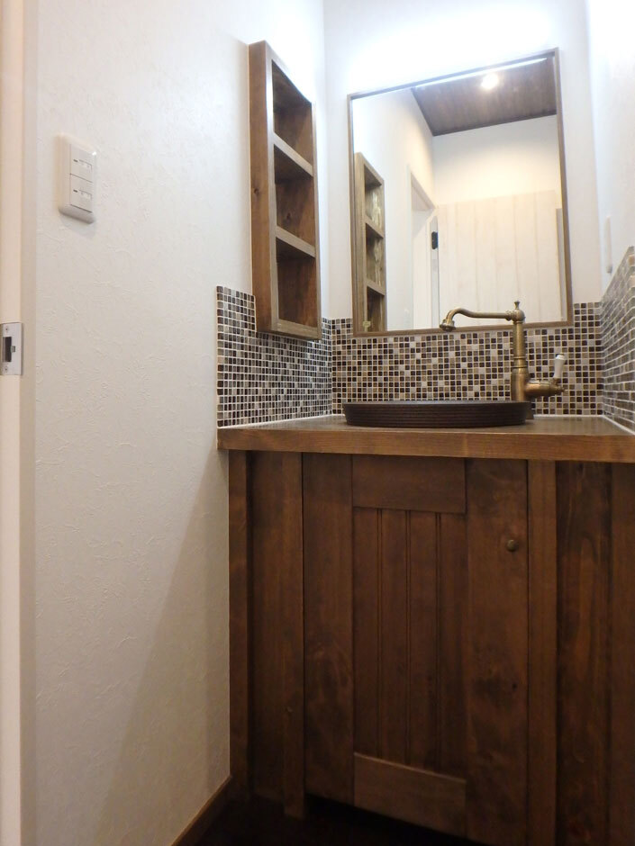 モザイクタイルが目を引く造作洗面台はアンティーク調の水栓を使用し、細かい部分にまでこだわりが。壁を使った収納でコンパクトながらも機能性に優れている