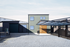 モスグリーンのガルバリウムに、縦のラインが美しい木格子がアクセントの外観。玄関への視線をカットしながらも圧迫感を与えず抜け感のあるアプローチです。