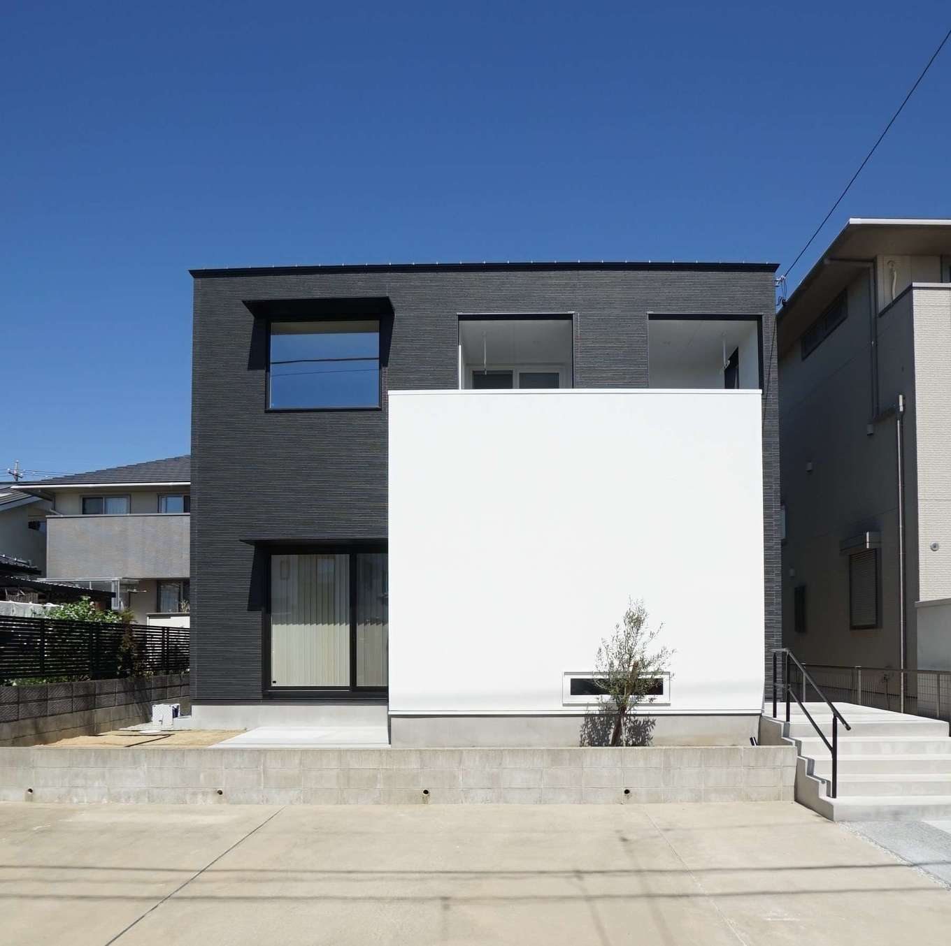 RIKYU 一級建築士事務所【デザイン住宅、間取り、建築家】黒いサイディングの外壁と、目隠しの白い塗り壁が絶妙に調和したシンプルモダンな外観。庭に奥さま専用の家庭菜園スペースもある