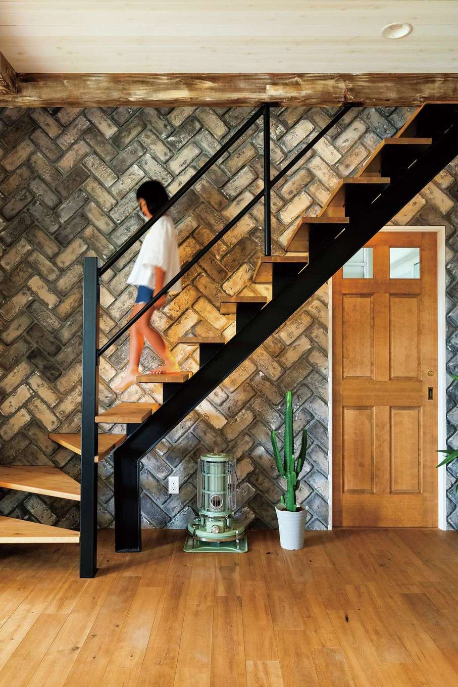 富士ホームズデザイン【デザイン住宅、建築家、インテリア】アンティークレンガのアクセントウォールがLDK全体をワンランク上の空間に引き立てている。木の階段やアイアンの手すりとの相性も抜群