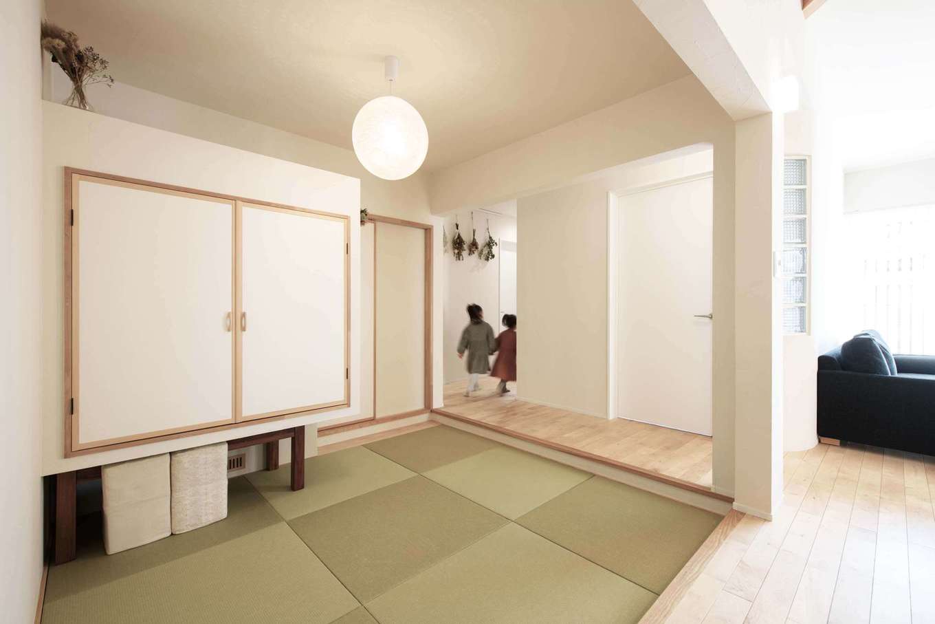 平屋建築ブルーハウス【デザイン住宅、子育て、平屋】リビングダイニングにつながる和室。床を一段下げ、なおかつ下り壁を設けてゾーン分けすることで、空間に落ち着きが生まれた。収納壁の下に座卓や座椅子をしまえるスペースを確保し、普段はすっきりとした状態をキープ。子どもが遊んだり、昼寝をしたりと、多目的に利用できる